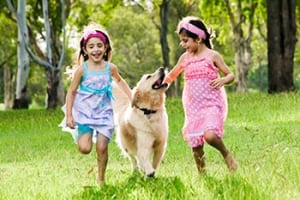 Young girls playing with their healthy dog who gets treated at Harmony Animal Hospital.