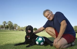 Black dog who is covered by insursance and his person, resting after a soccer game.